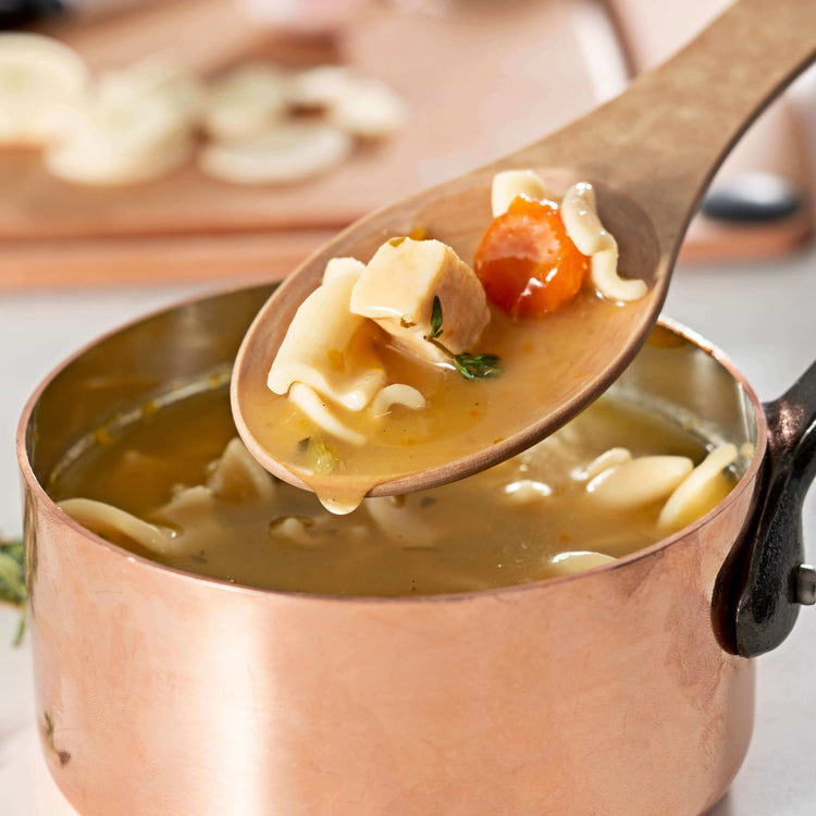 Kitchen Series Medium Spoon in Natural scooping up some chicken noodle soup