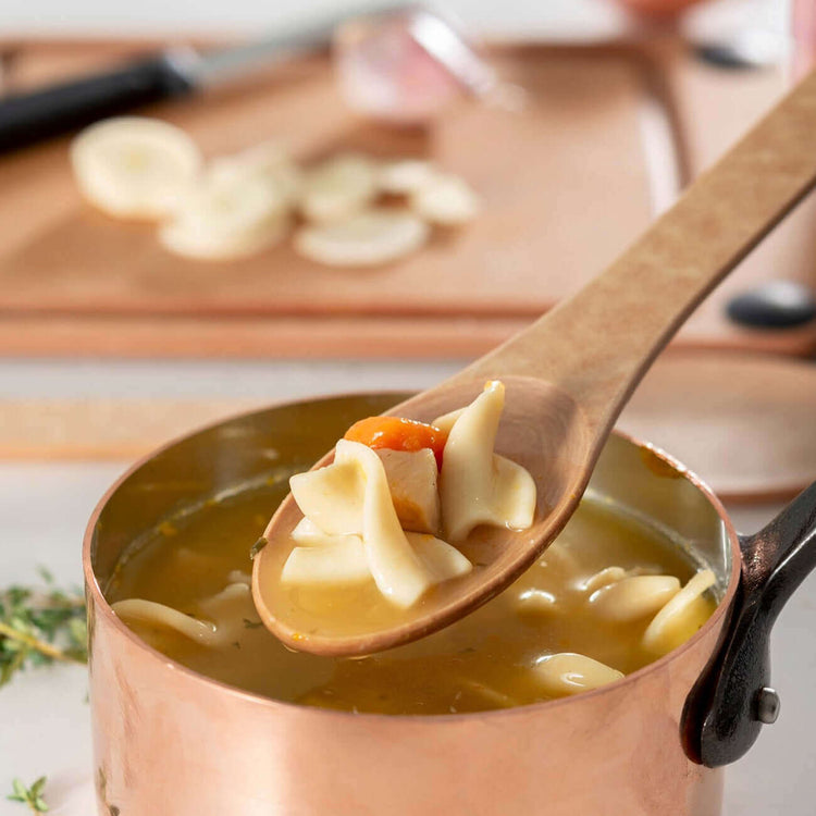Kitchen Series Small Spoon in Natural scooping up some chicken noodle soup